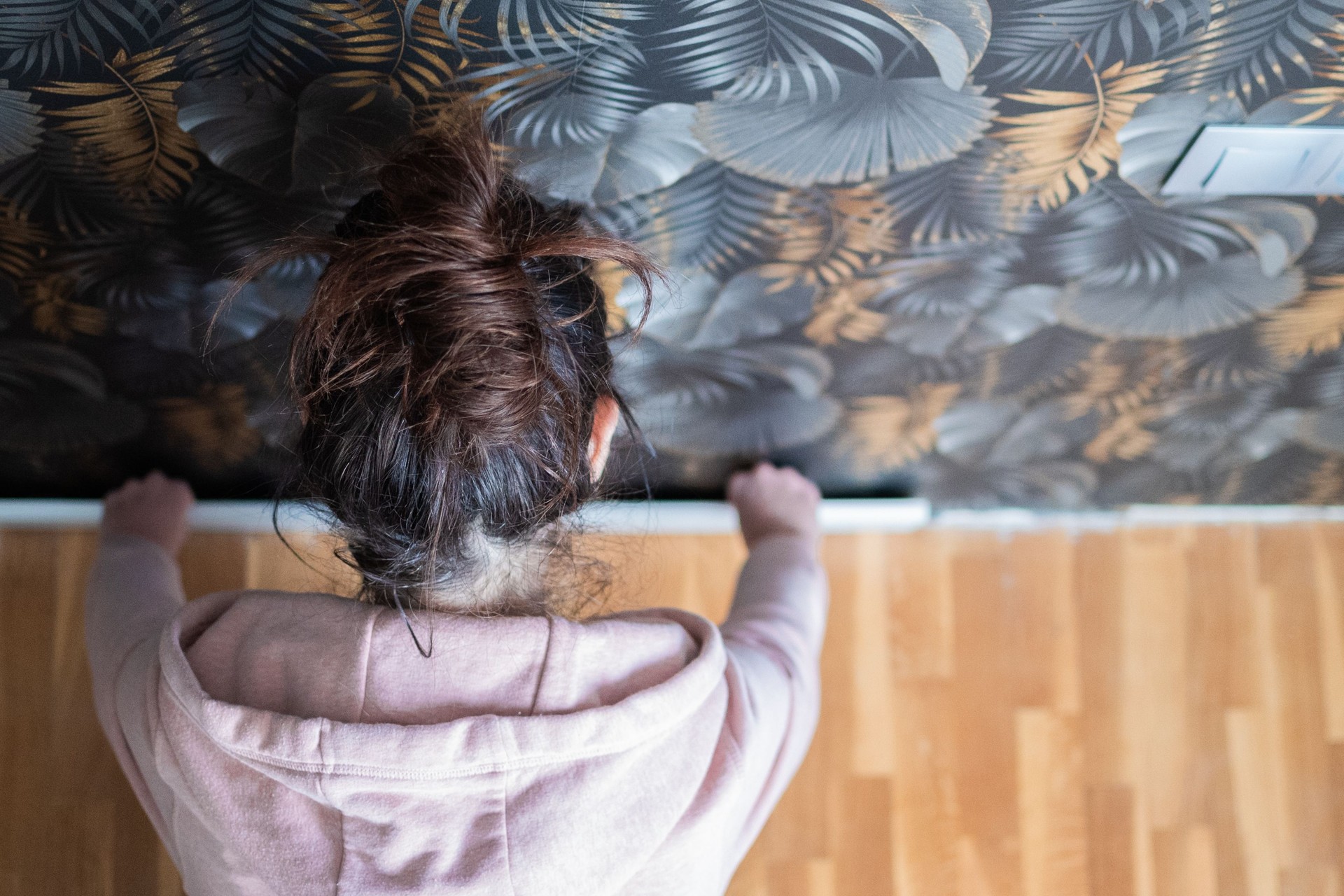 Woman installing wallpaper in home renovation project